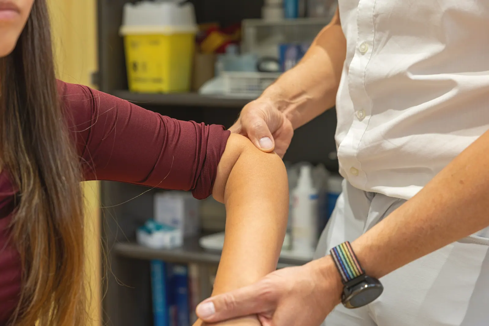 Dr. Lukas untersucht das Knie einer Patientin mit beiden Händen